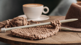 Image of knitting project and a coffee in the background on a table