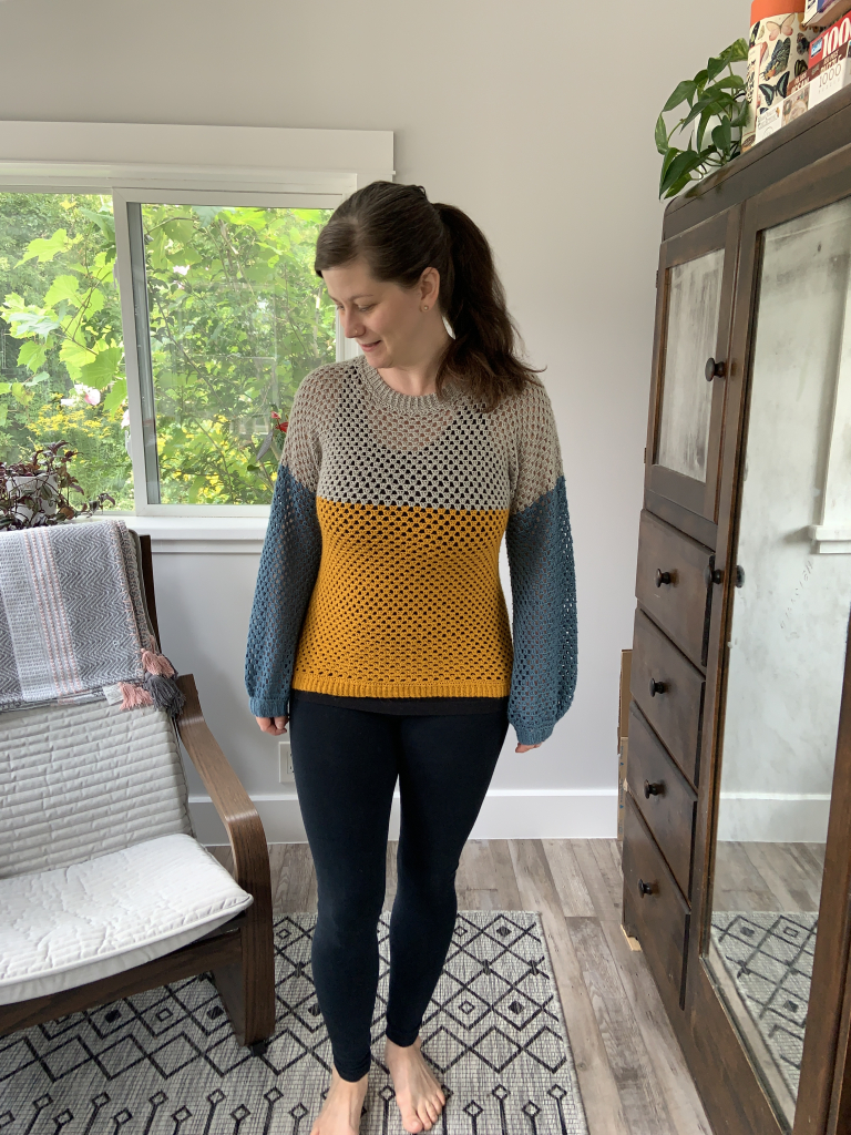 Maker modelling the finished Hobbii Pullover in ochre, grey and teal