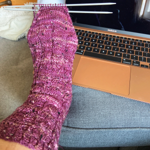 Image of one completed sock with lace details in a beautiful heather purple. 